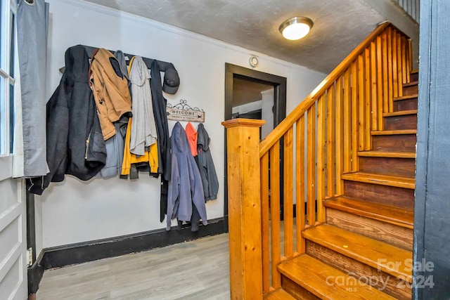 stairs featuring wood-type flooring and ornamental molding