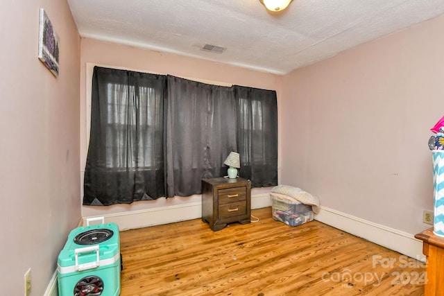 bedroom with hardwood / wood-style floors and a textured ceiling