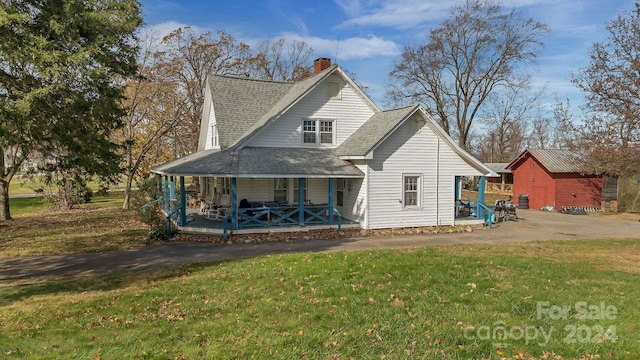 back of property featuring a lawn and covered porch