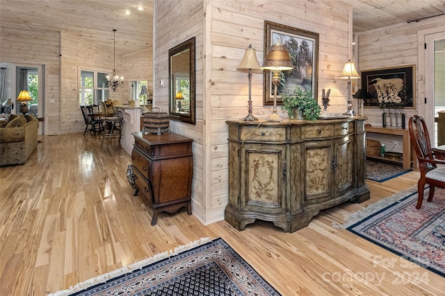 interior space with wood ceiling, high vaulted ceiling, a notable chandelier, light hardwood / wood-style floors, and wood walls