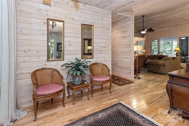 living area featuring ceiling fan, wood walls, wood ceiling, and light hardwood / wood-style flooring