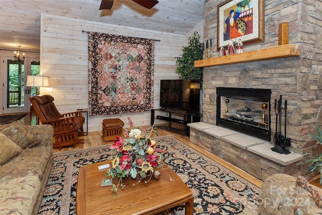 living room featuring hardwood / wood-style floors, wood walls, wooden ceiling, ceiling fan, and a fireplace