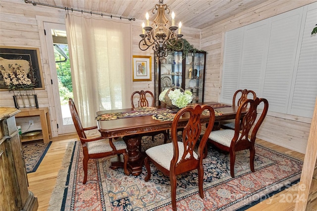 dining area with a notable chandelier, wood walls, light wood-type flooring, and wooden ceiling