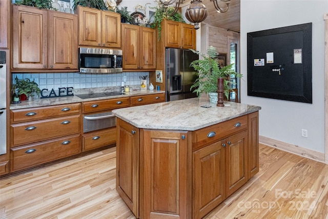 kitchen with decorative backsplash, a center island, light wood-type flooring, and appliances with stainless steel finishes