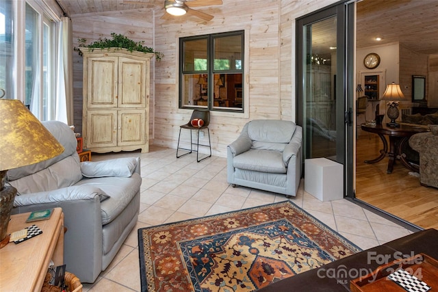 tiled living room with ceiling fan, wood walls, and lofted ceiling