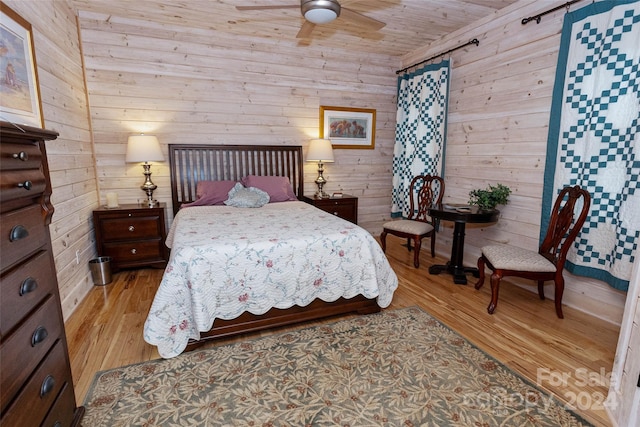 bedroom featuring ceiling fan, wood ceiling, wooden walls, and light hardwood / wood-style flooring