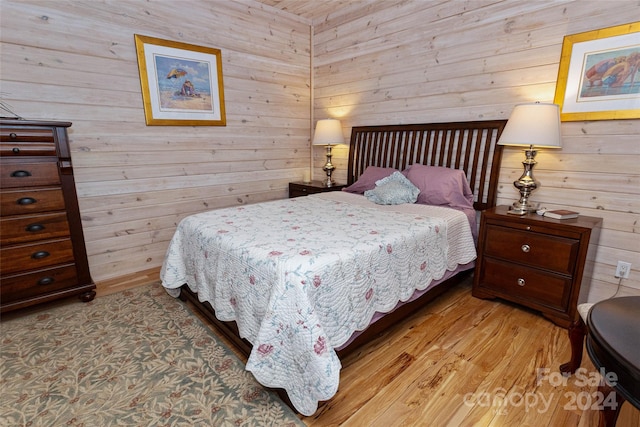 bedroom with wooden walls and light hardwood / wood-style flooring