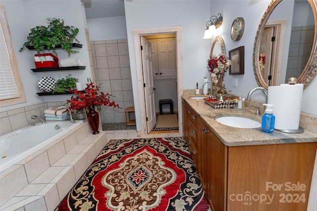 bathroom with vanity, a relaxing tiled tub, and tile patterned floors