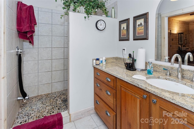 bathroom with tile patterned flooring, vanity, and a tile shower