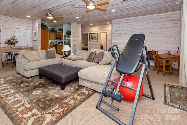 living room featuring carpet flooring, ceiling fan, wood walls, and wood ceiling