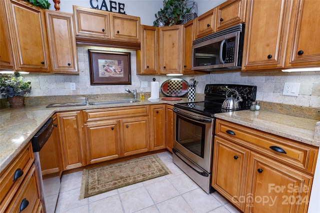 kitchen with backsplash, light stone counters, light tile patterned floors, and appliances with stainless steel finishes