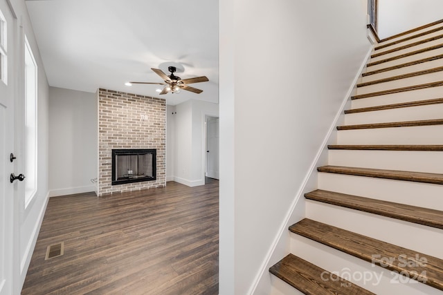 staircase featuring ceiling fan, wood-type flooring, and a fireplace