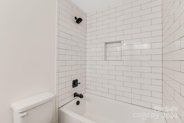 bathroom with toilet and tiled shower / bath