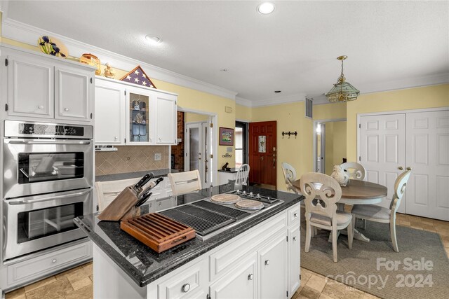 kitchen featuring stainless steel double oven, a kitchen island, tasteful backsplash, decorative light fixtures, and white cabinets