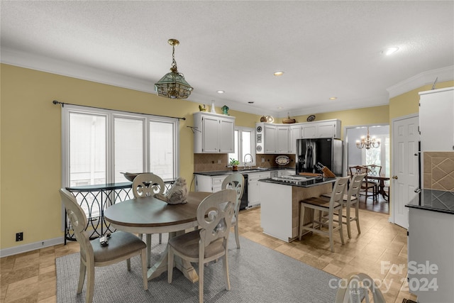 dining space with crown molding, sink, a chandelier, and a textured ceiling