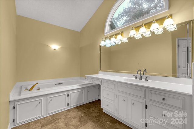 bathroom with a bathtub, vanity, and vaulted ceiling