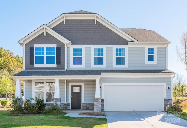 craftsman-style house featuring a front lawn, covered porch, and a garage