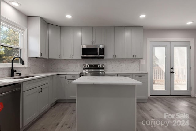 7704 Cedar Bluff Ln, Charlotte, NC 28227 - kitchen with a center island, sink, light hardwood / wood-style flooring, light stone countertops, and appliances with stainless steel finishes