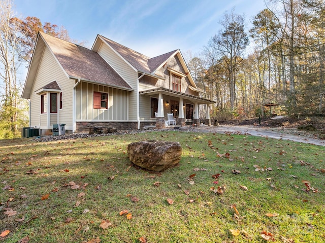 exterior space with central AC unit, a porch, and a yard