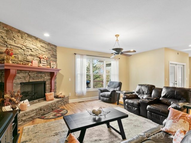 living room with a fireplace, light wood-type flooring, and ceiling fan