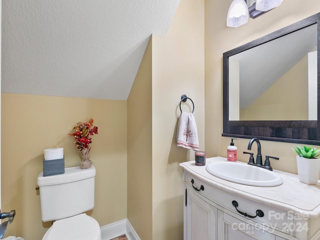 bathroom featuring vanity, vaulted ceiling, and toilet