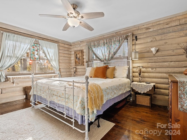 bedroom featuring log walls, dark hardwood / wood-style flooring, and ceiling fan