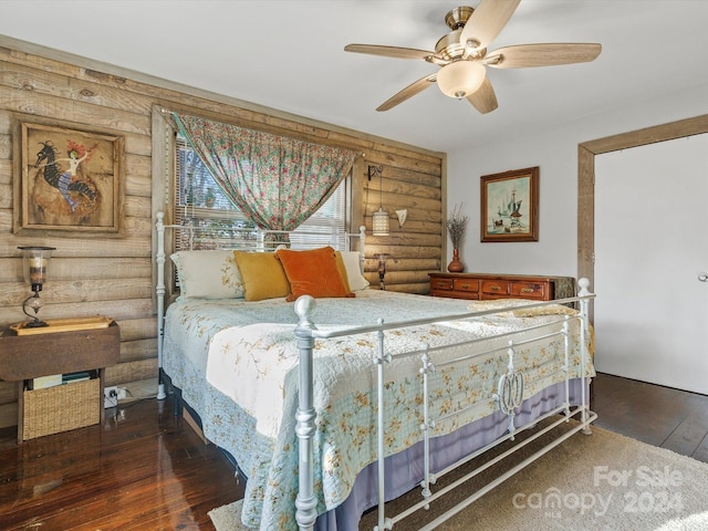 bedroom with rustic walls, ceiling fan, and dark wood-type flooring