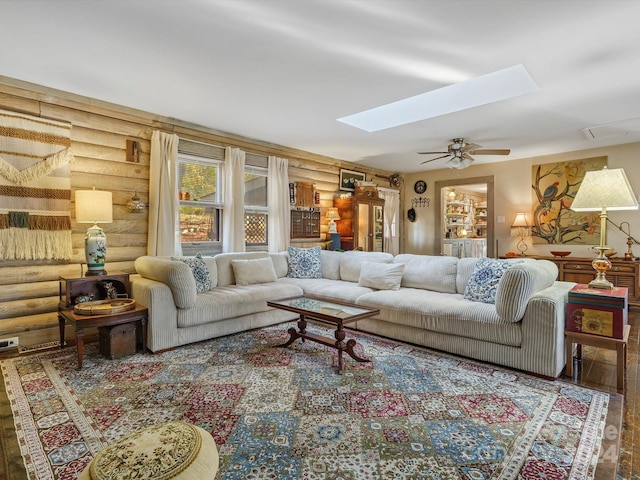 living room with hardwood / wood-style flooring, ceiling fan, and rustic walls