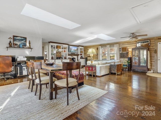 dining room with a skylight, ceiling fan, dark hardwood / wood-style flooring, and wooden walls