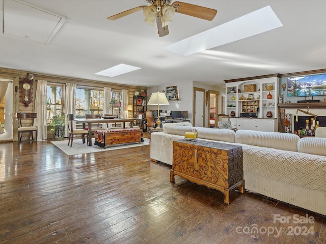 living room featuring dark hardwood / wood-style floors, ceiling fan, and a skylight