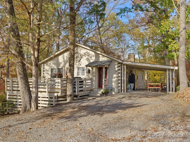 view of front of property with driveway, a chimney, and an attached carport