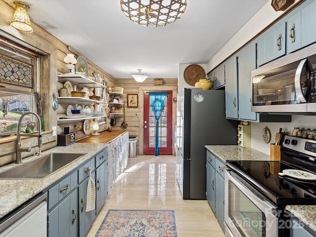 kitchen featuring blue cabinets, stainless steel appliances, light countertops, and a sink