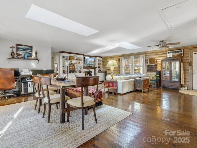 dining area with wood-type flooring, a skylight, and a ceiling fan