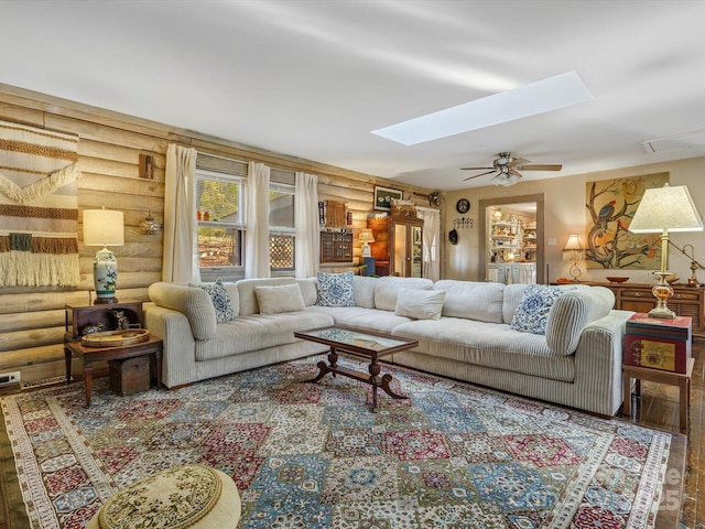 living area featuring wood finished floors, a skylight, a ceiling fan, and log walls