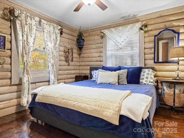 bedroom with rustic walls, wood-type flooring, and ceiling fan