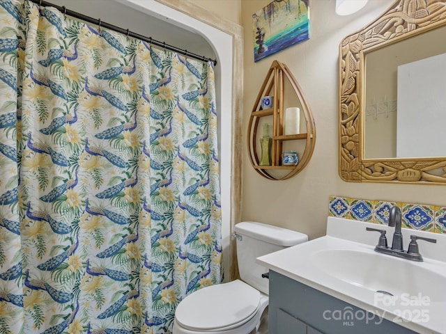 bathroom featuring a shower with shower curtain, toilet, and vanity