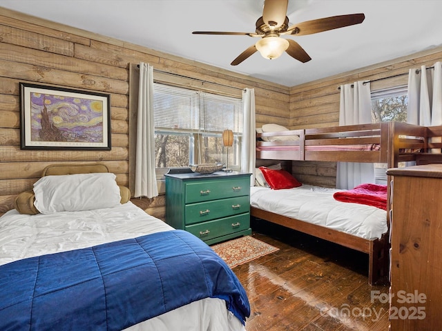 bedroom featuring rustic walls, ceiling fan, and dark wood finished floors