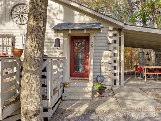 view of exterior entry with board and batten siding and log exterior
