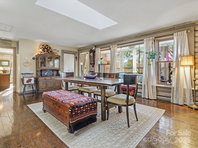 dining space with attic access, wood-type flooring, baseboards, and a skylight