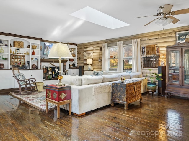 living room featuring hardwood / wood-style floors, a ceiling fan, rustic walls, and a skylight