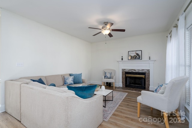 living room with ceiling fan, hardwood / wood-style floors, and a tile fireplace