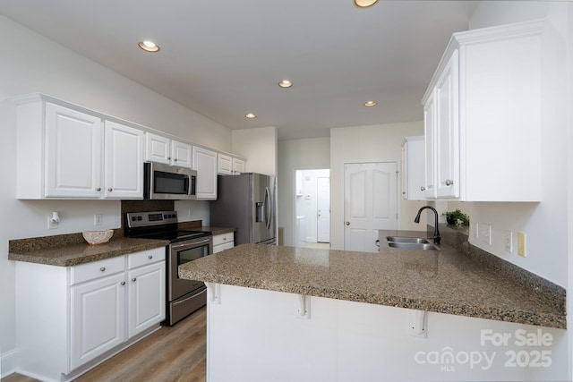 kitchen featuring sink, white cabinets, kitchen peninsula, and appliances with stainless steel finishes