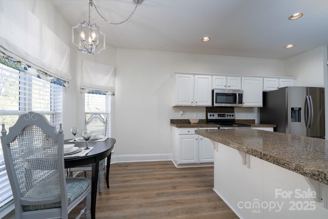 kitchen featuring white cabinets, stainless steel appliances, and decorative light fixtures