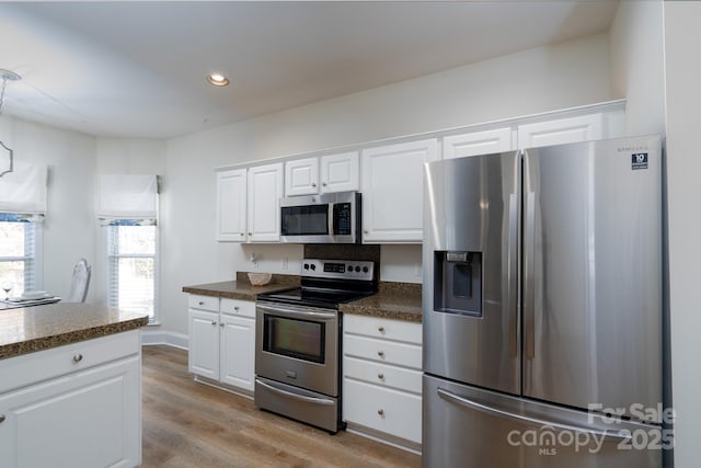 kitchen with white cabinets, appliances with stainless steel finishes, and light hardwood / wood-style flooring