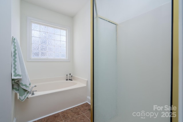 bathroom with a tub to relax in and tile patterned floors