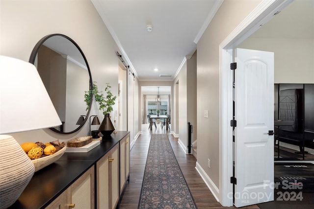 hall with dark hardwood / wood-style floors, a barn door, and ornamental molding