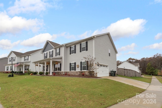 view of front of property featuring a front yard, a garage, and covered porch