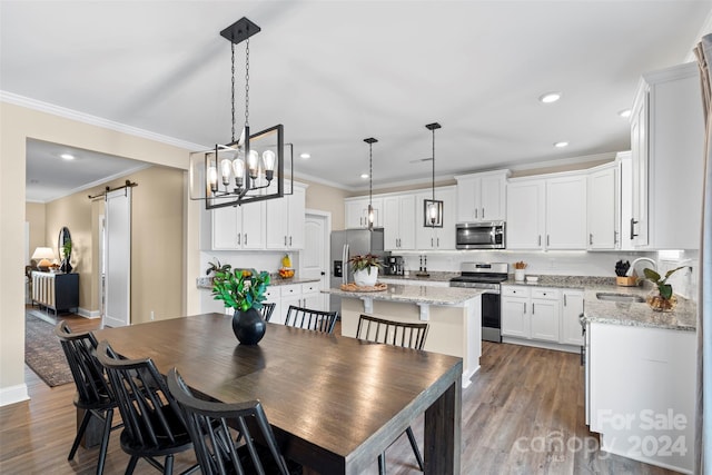 dining space featuring a barn door, wood-type flooring, sink, and ornamental molding