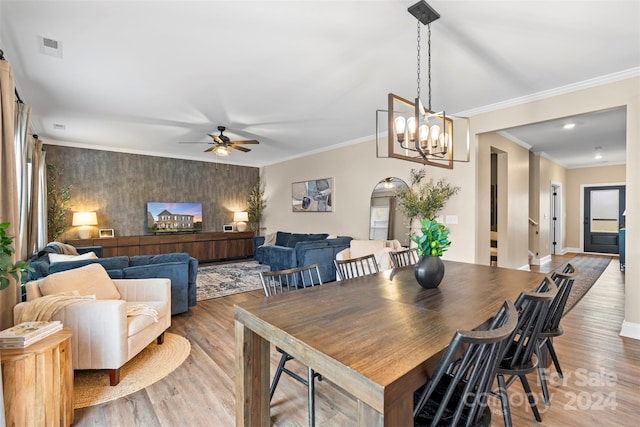 dining space with hardwood / wood-style floors, ceiling fan with notable chandelier, and ornamental molding