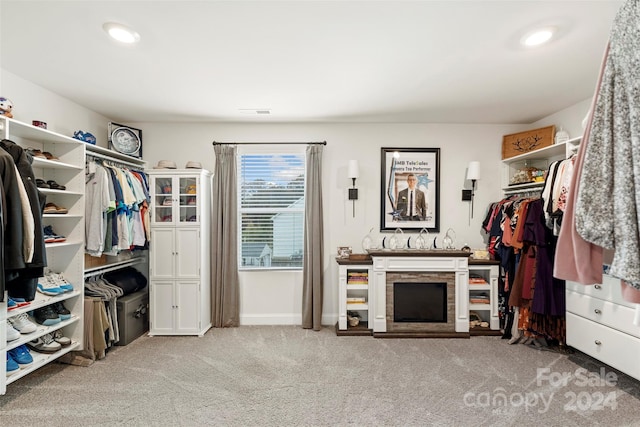 spacious closet with a stone fireplace and light carpet